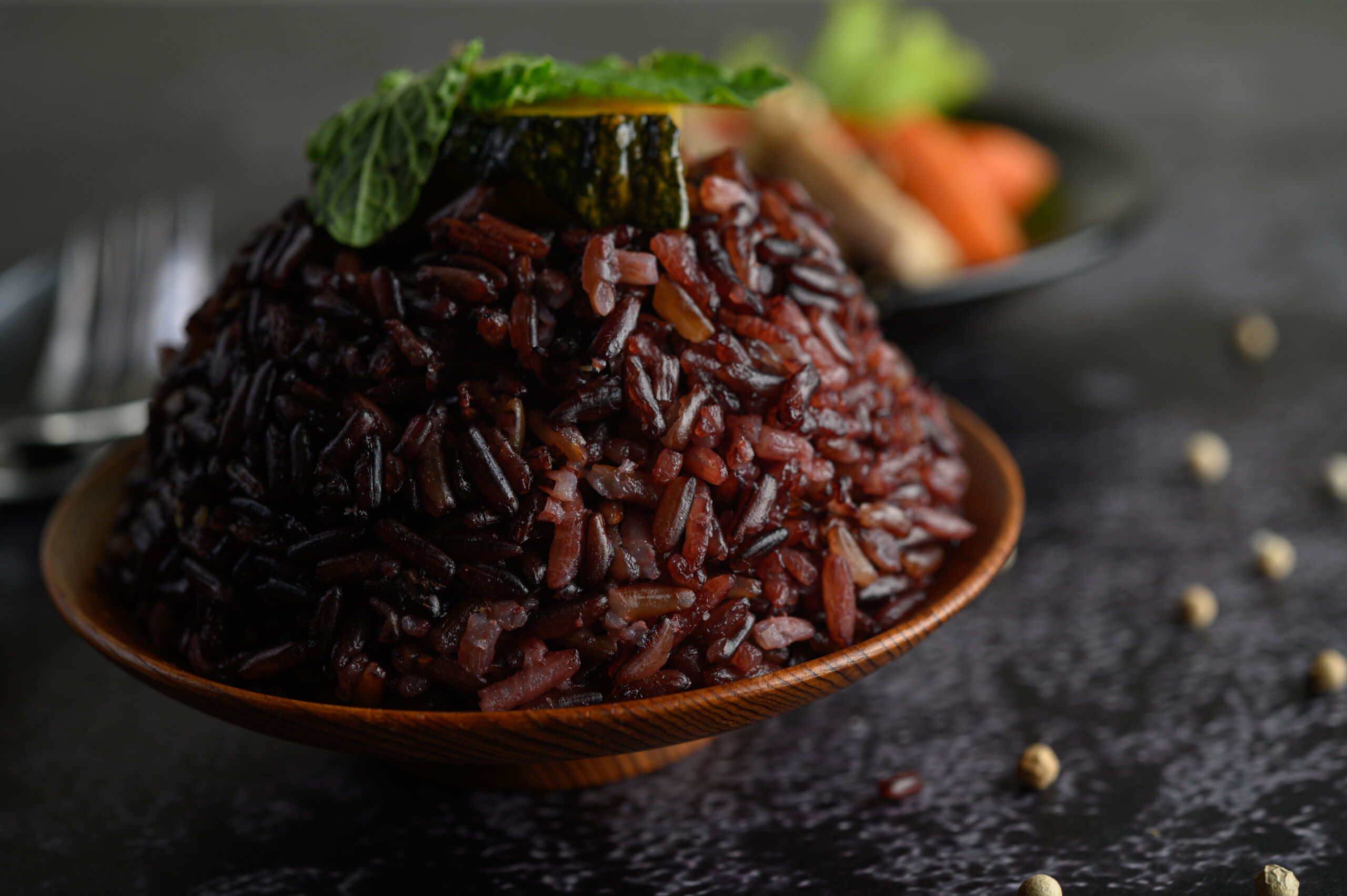 Purple rice berries cooked in a wooden dish with mint leaves. Selective focus